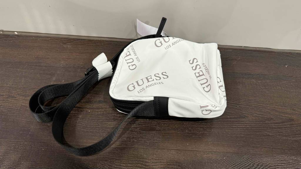Brustbeutel-Test: Ein weißes Modell der Marke Guess liegt mit der Rückseite nach oben auf einer Holzoberfläche.