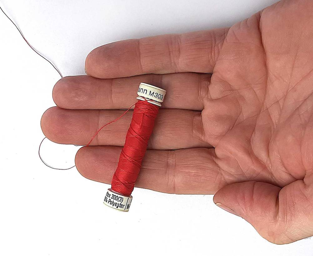 Eine Hand hält ein rotes Gütermann-Nähgarn im Test.