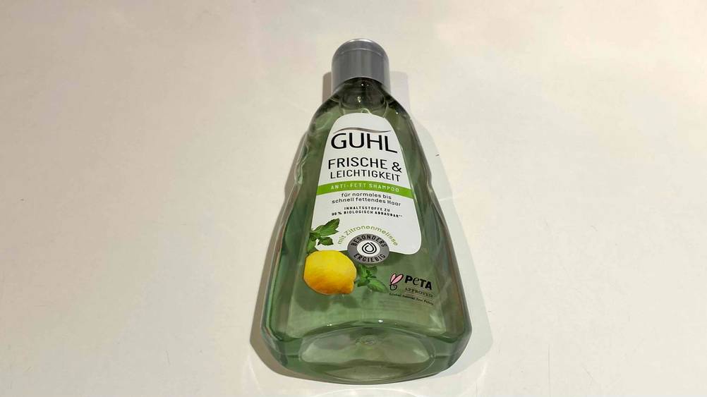 Die Flasche des getesteten Guhl-Shampoos mit dem Boden nach vorne auf einer hellen Fläche liegend.