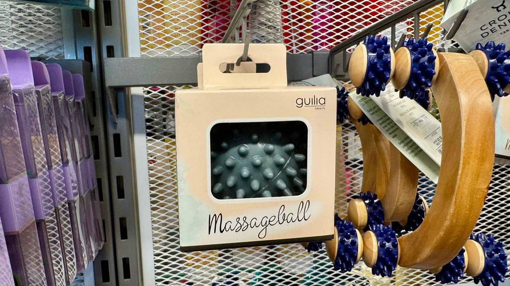 Ein original verpackter Massagebälle im Test hängt an einem Verkaufsregal neben weiteren Massageutensilien.