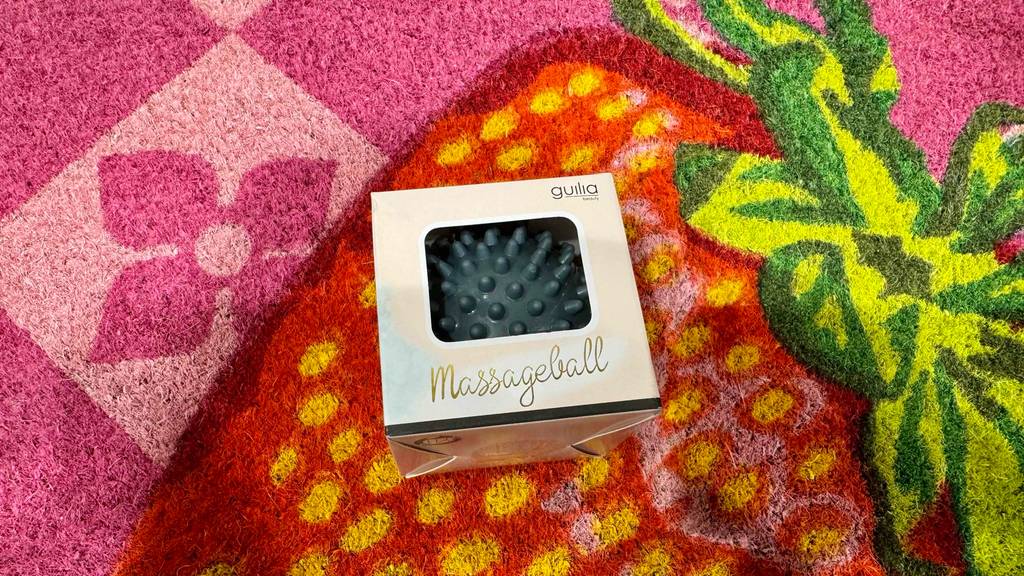 Massageball-Test: Ein Noppenball in seiner Verpackung liegt auf einem bunten Teppich