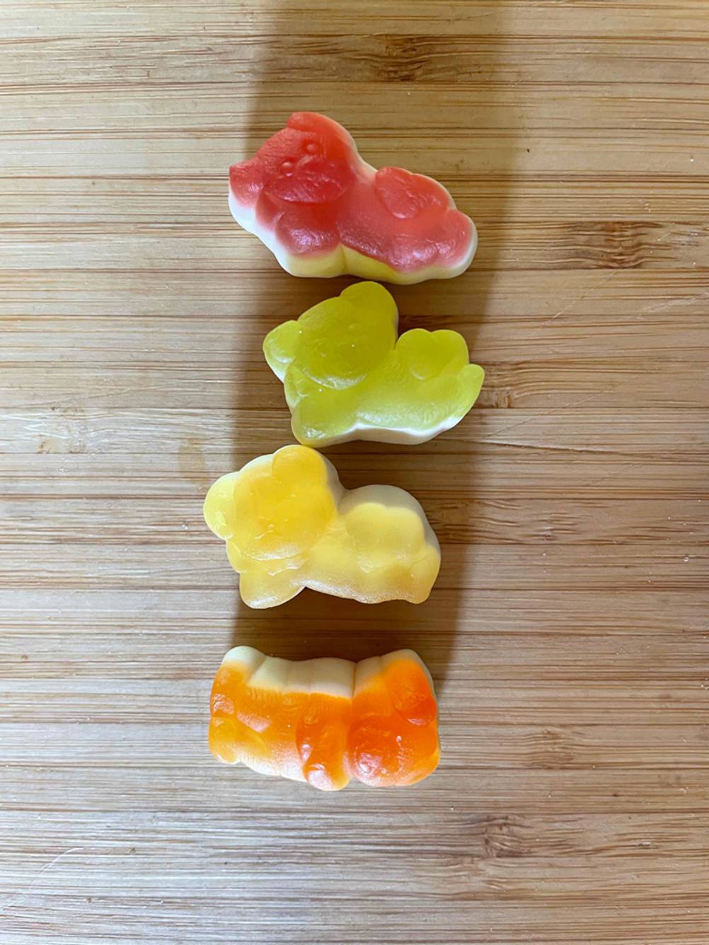 Mehrere Gummibärchen im Test: Vier verschiedene Gummibärchen liegen auf dem Holztisch. 