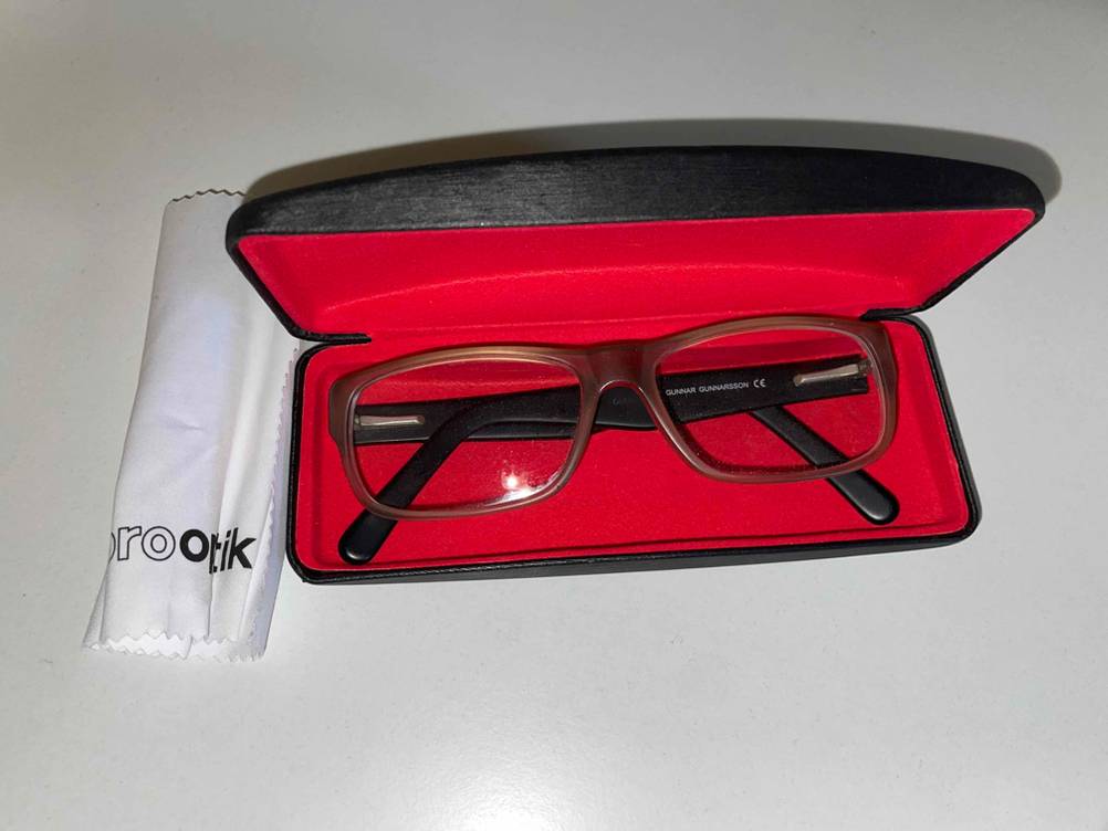 Brille in Brillenetui mit Brillenputztuch daneben.