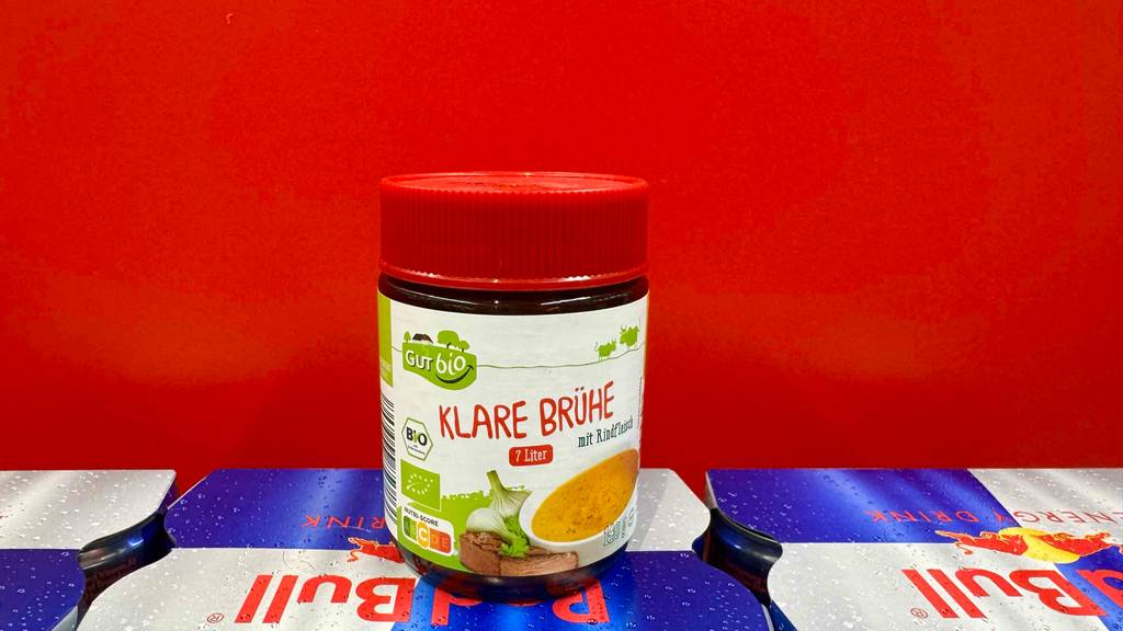Eine getestete klare Brühe in der 140-g-Dose mit Schraubdeckel steht vor einem roten Hintergrund.