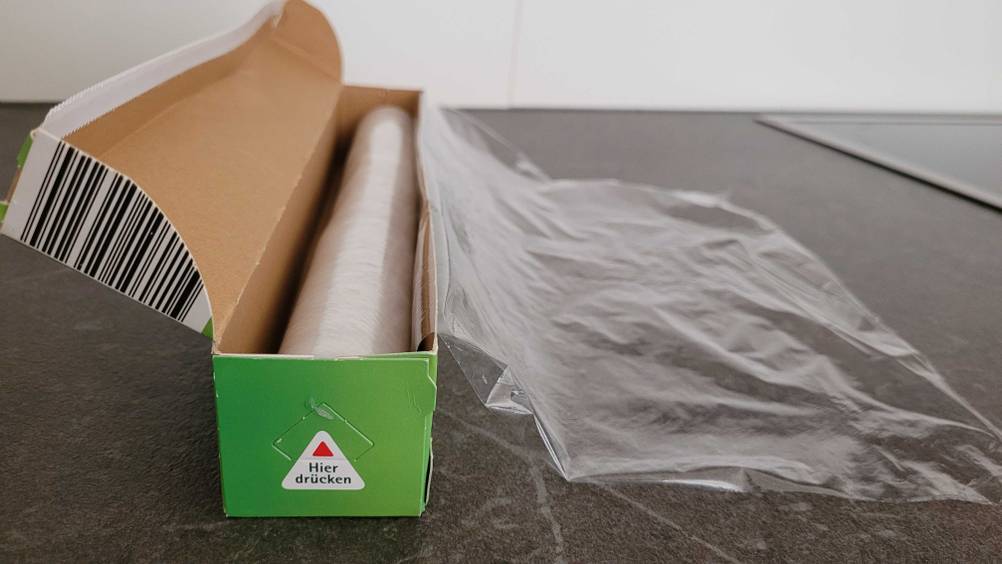 Ein Stück Frischhaltefolie ist zum testen aus einer Verpackung gezogen.