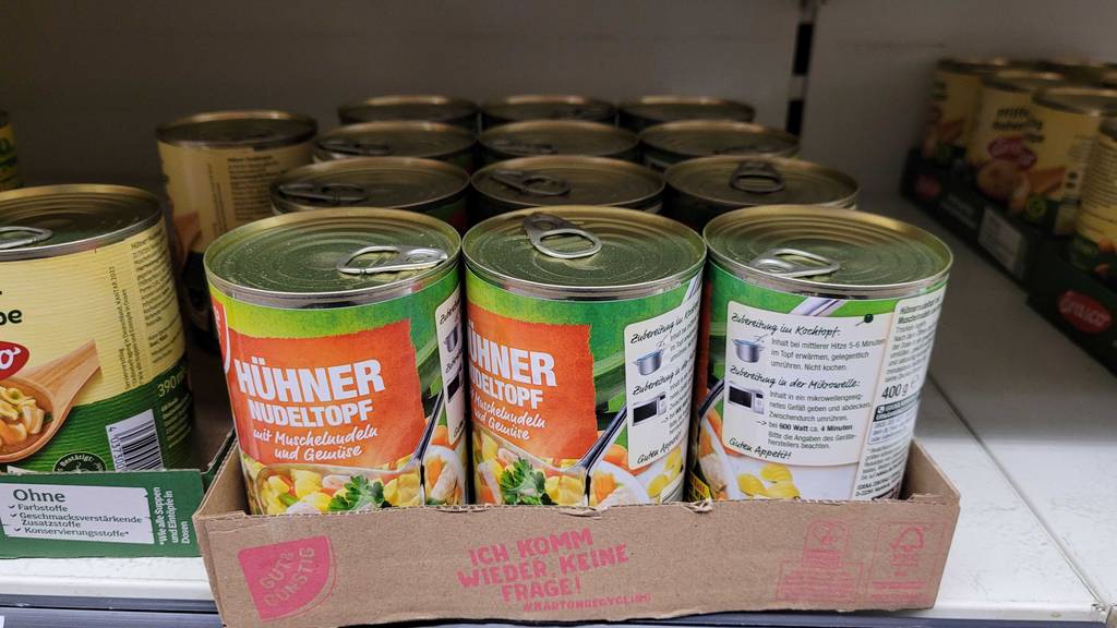 Mehrere Dosen Hühnersuppe im Test befinden sich in einem Karton auf dem Verkaufsregal.