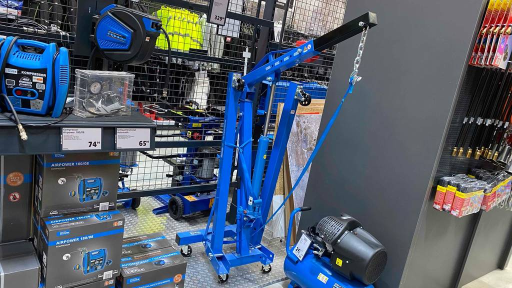 Gesamtansicht von einem blauen Werkstattkran im Test. Das klappbare Modell ist mit Rollen und einem verlängerbaren Hebearm ausgestattet.
