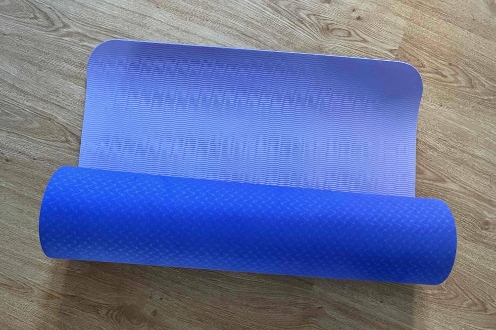Im Test: Gymnastikmatte in lila liegt gerollt auf Holzboden.