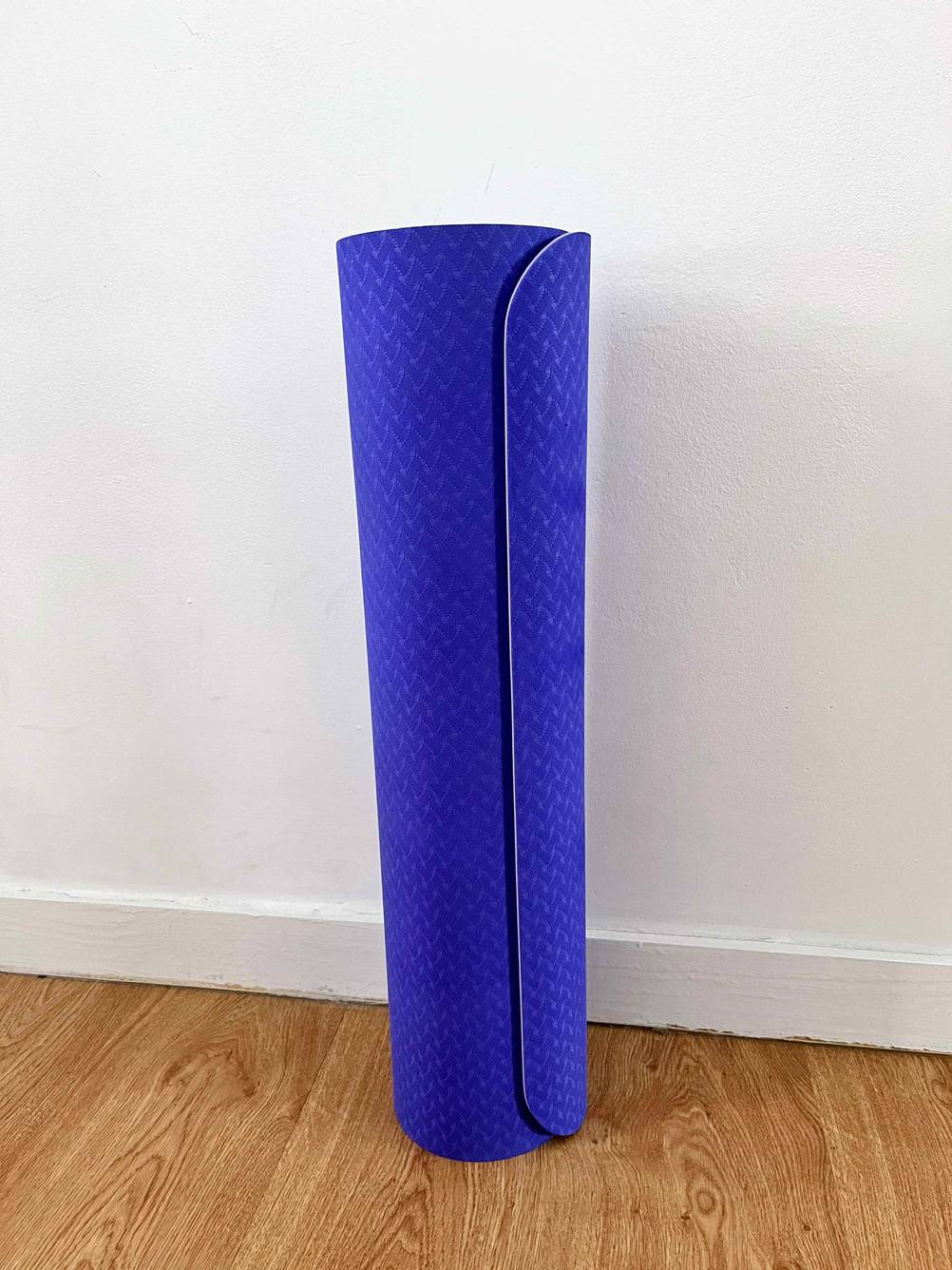 Im Test: Eine Gymnastikmatte steht zusammengerollt vor einer weißen Wand.