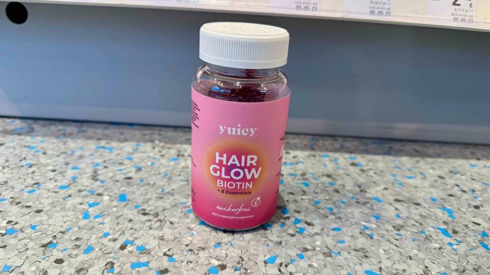 Vor einem Verkaufsregal mit Preisangaben steht eine Dose der getesteten Haar-Gummibärchen auf dem Boden.