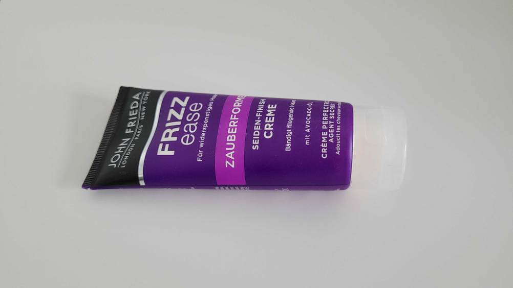 Eine Tube Haarcreme im Test von der Seite auf einer hellen Fläche liegend.