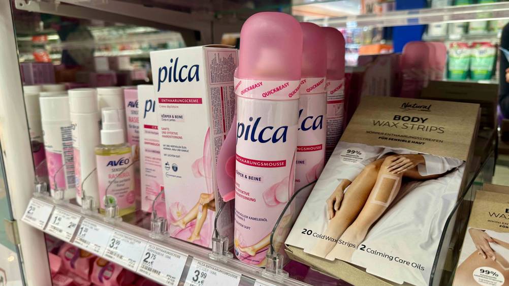 Ein getestetes Haarentfernungsspray neben anderen Produkten in einem Verkaufsregal.