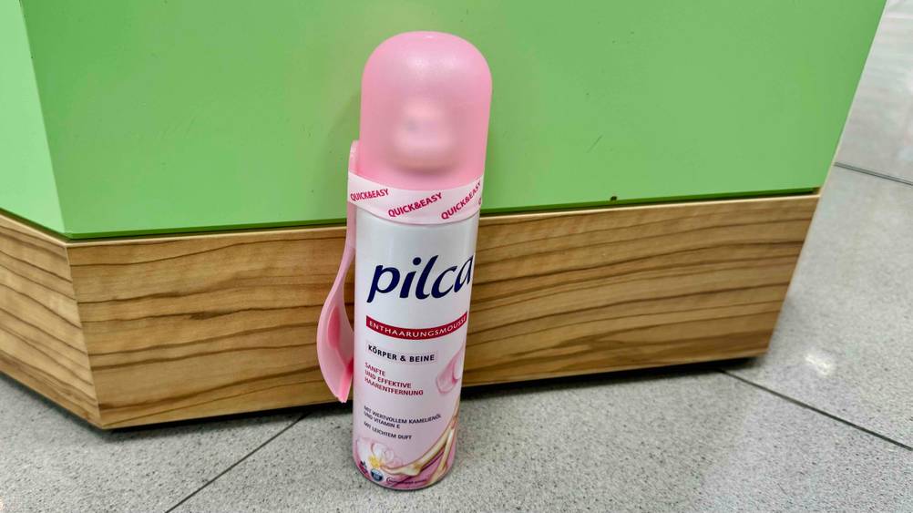Eine Dose des Haarentfernungssprays im Test vor einer grünen Wand stehend.