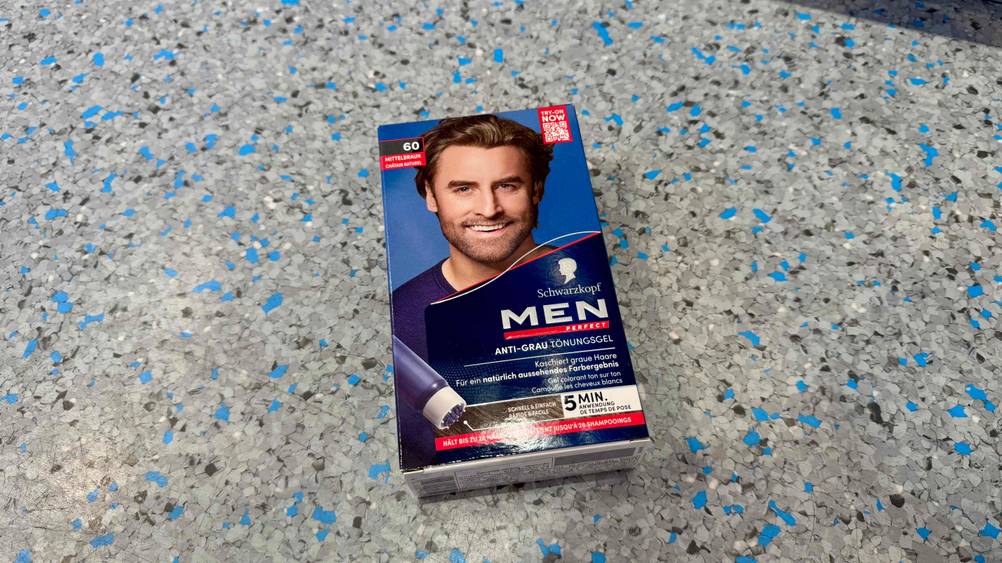 Auf einem Boden liegt eine Packung des getesteten Haarfärbemittel für Männer.