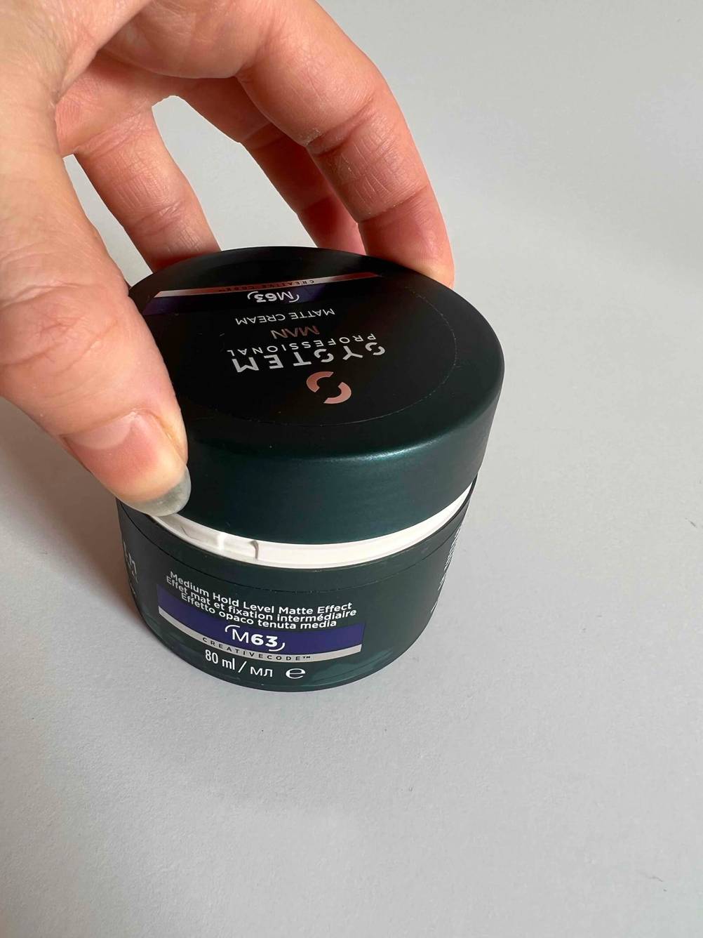 Eine Hand öffnet eine getestete Haargel-Packung. 