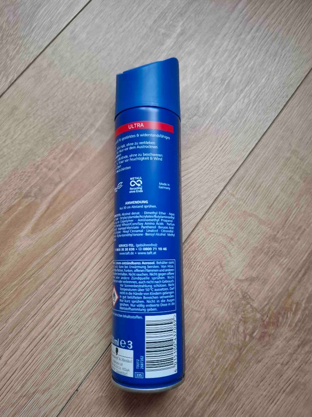Ein getesteter Haarlack liegt mit der Rückseite nach oben auf einem Holzboden.