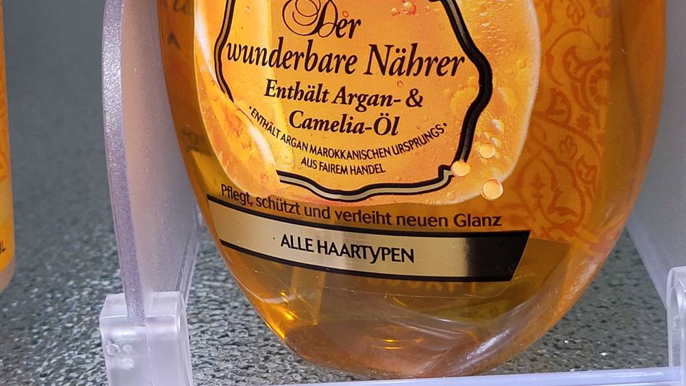 Nahaufnahme der Informationen auf der Vorderseite unten einer Flasche des getesteten Haaröls.