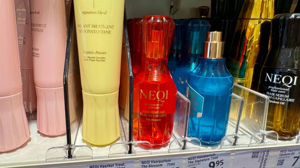 Ein Haarparfum im Test neben anderen Produkten in einem Verkaufsregal.