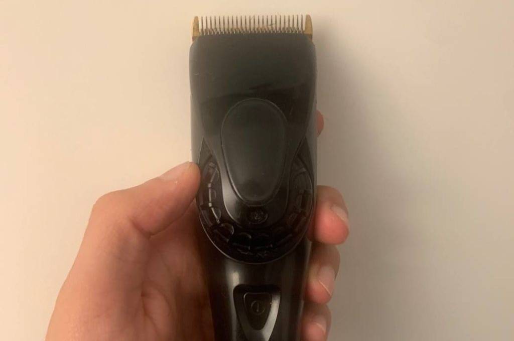 Haarschneider-Test: Hand hält einen schwarzen Haarschneider der Marke Panasonic vor heller Wand.