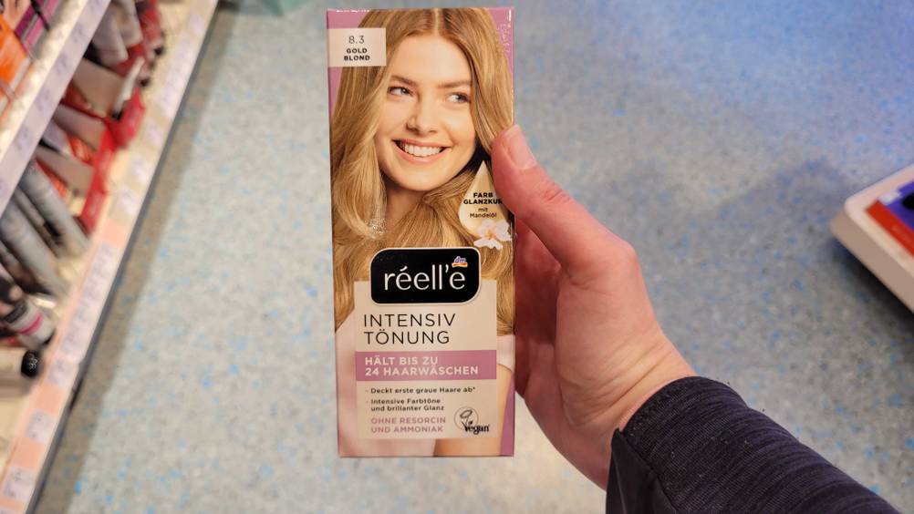Eine Hand hält die getestete Haartönung blond hoch.