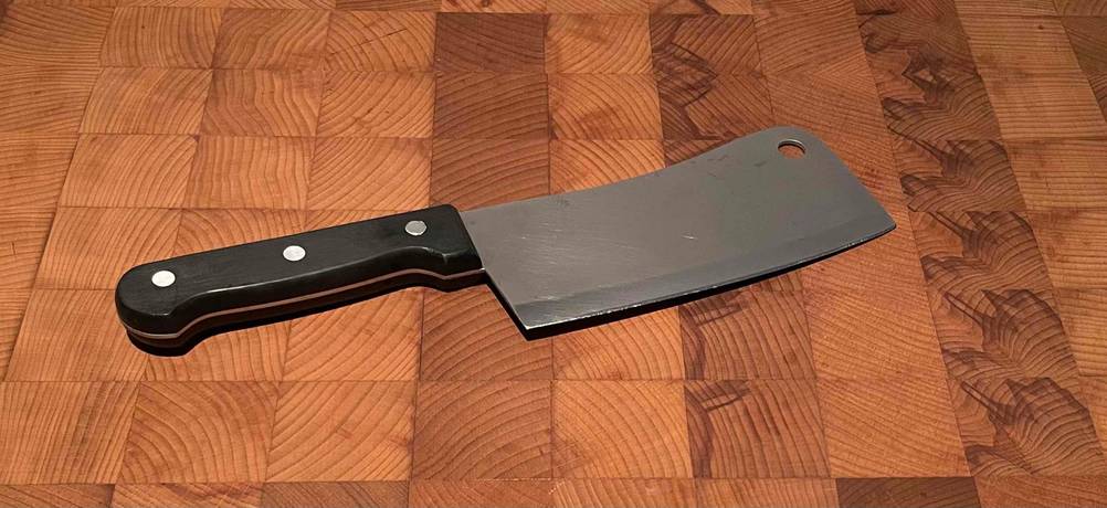 Ein Küchenmesser befindet sich auf einem getesteten Hackblock aus Holz. 