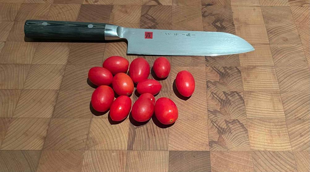 Tomaten und Küchenmesser befinden sich auf einem getesteten Hackblock aus Holz.