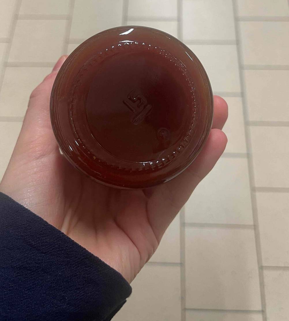Im Test: Eine Hand hält ein Glas Hagebuttenmarmelade mit der Unterseite nach oben.