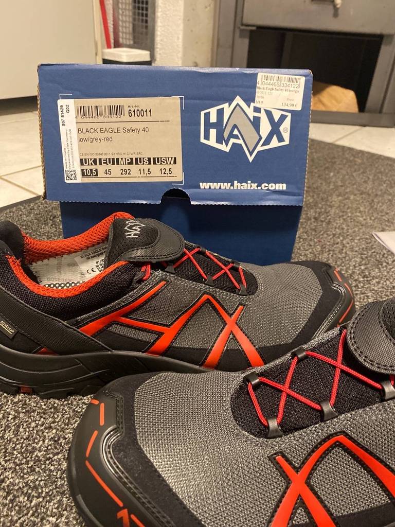 Ein Paar neue Haix Sicherheitsschuhe für den Test stehen vor ihrem Schuhkarton. Sie sind im grau-schwarz und orangen Design gefertigt.