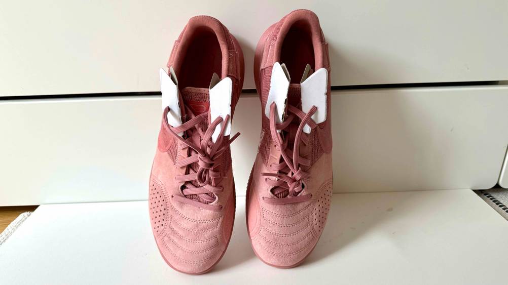 Ein Paar Hallenschuhe Damen auf der Spitze stehend an einer hellen Wand von oben.