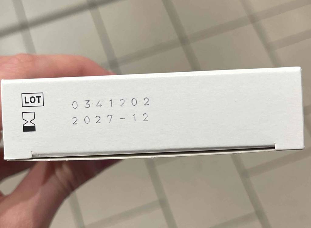 Ansicht der schmalen Seite einer weißen Verpackung, inklusive der Produktnummer und des Haltbarkeitsdatums der getesteten Halsschmerztabletten.