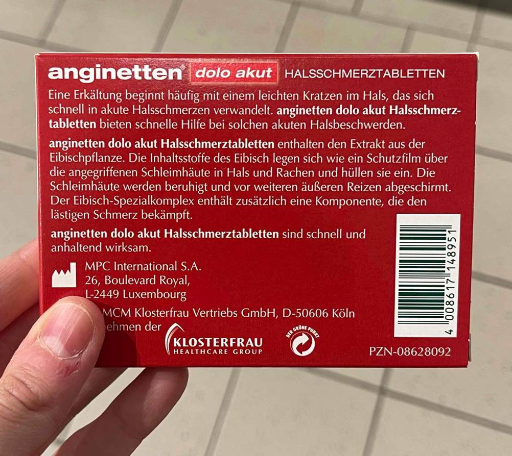 Ansicht der roten Rückseite einer Verpackung mit der Beschreibung von anginetten-Halsschmerztabletten im Test.