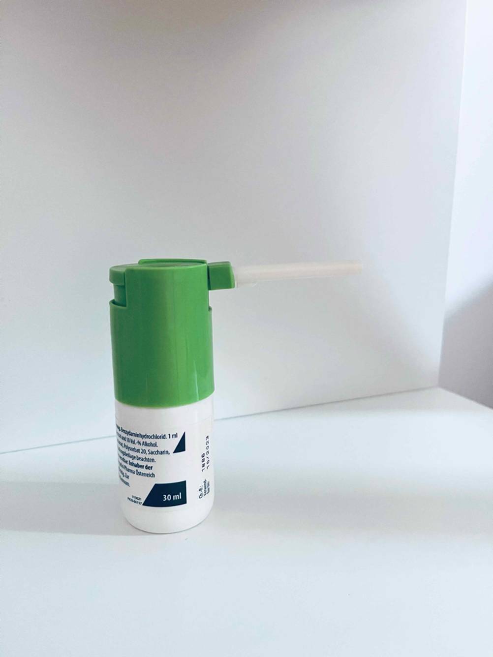Ein getestetes Halsspray von der Seite auf einer hellen Fläche stehend.