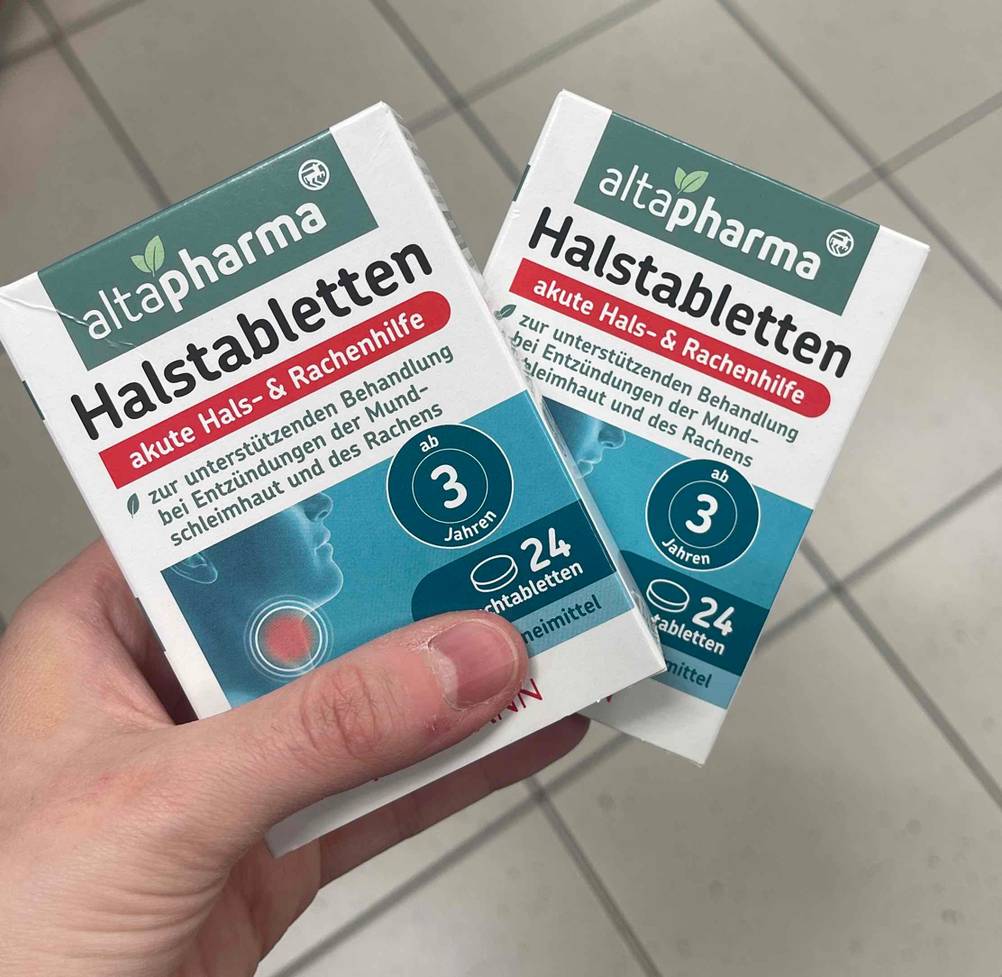 Eine Hand hält zwei Packungen Halstabletten zum testen.