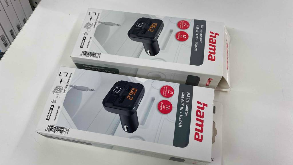 Zwei Hama-Verpackungen mit FM-Transmittern im Test befinden sich auf einem weißen Tisch.