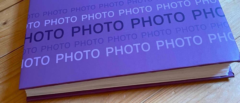 Fotoalbum-Test: Ein getestetes lila Fotalbum mit dem Schriftzug Photo liegt auf einem Holzboden.