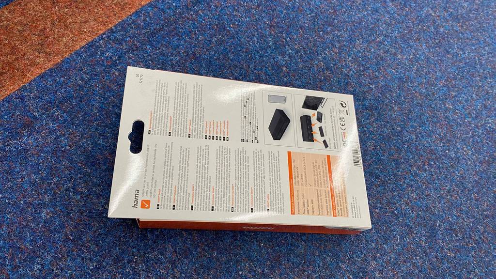 Verpackung eines getesteten HDMI-Switch liegt quer mit der Rückseite nach oben auf blauem Teppich.