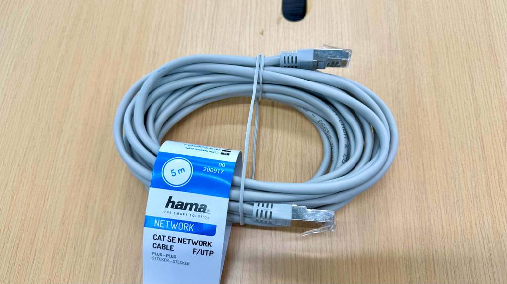 Ein getestetes Netzwerkkabel liegt aufgerollt auf einem Holztisch.