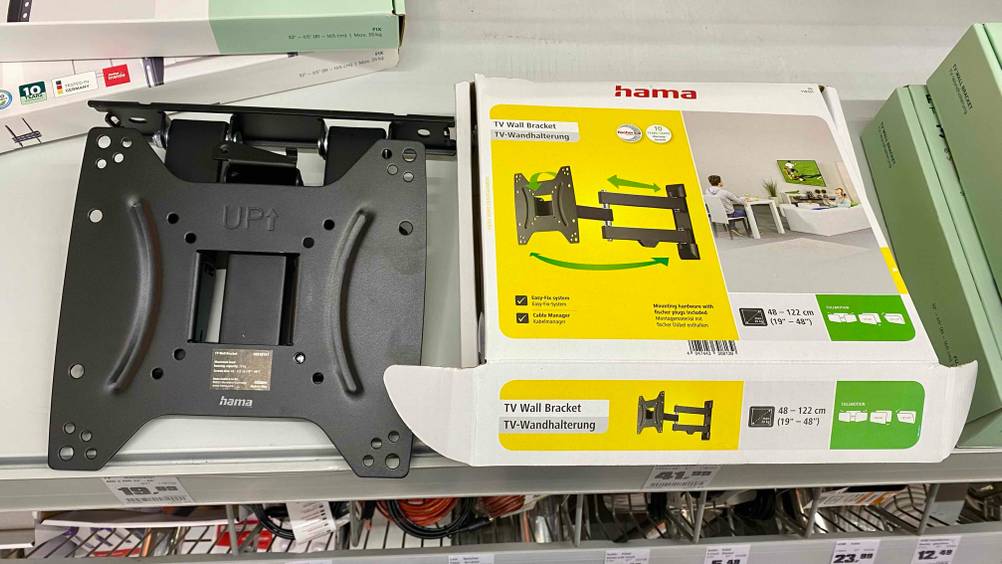 Im Test: Eine TV-Wandhalterung liegt neben der Originalverpackung mit Infografiken.
