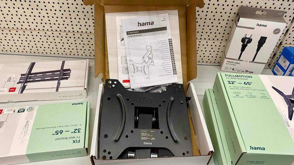 Eine getestete TV-Wandhalterung von hama in ihrem geöffneteten Karton von vorne mit Bedienungsanleitung.
