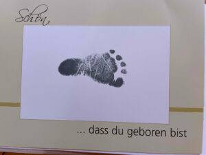 Fotoalbum getestet: Ein Babyfußabdruck auf einem weißen Papier mit Beschriftung.