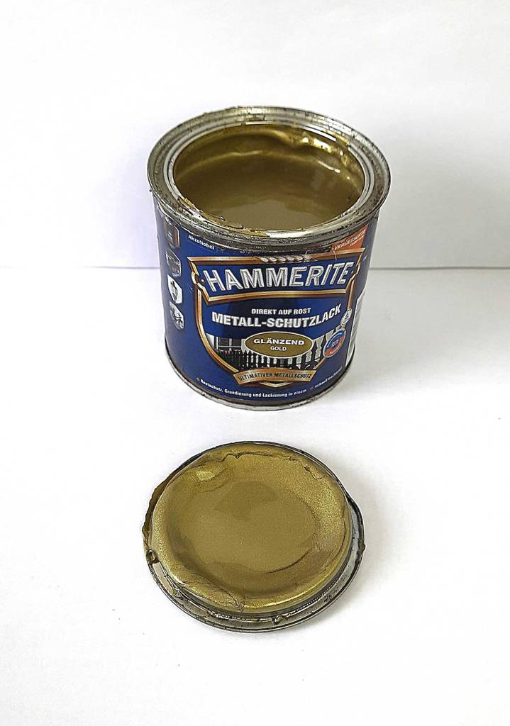 Im Test: Goldlack in der geöffneten Dose befindet sich hinter dem auf einer weißen Fläche liegenden Deckel.