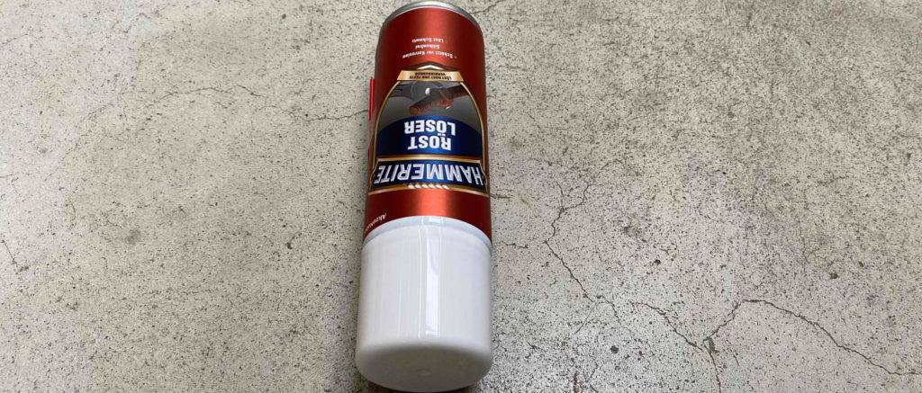 Der getestete Rostlöser liegt auf einem grauen Boden.