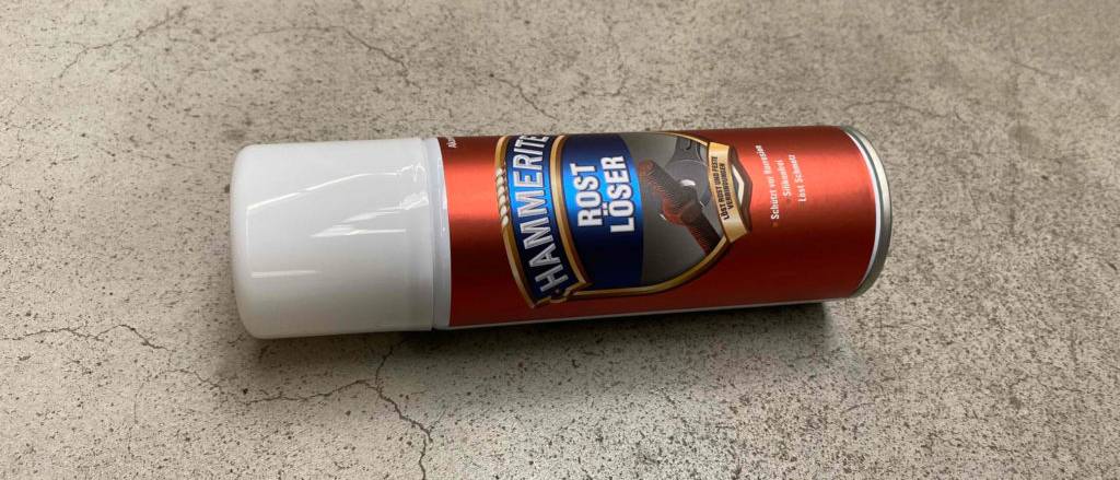 Der getestete Rostlöser liegt auf einem grauen Untergrund.