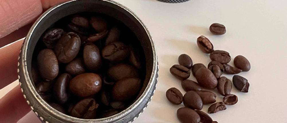 Kaffeebohnen in einer Hand-Kaffeemühle aus Stahl