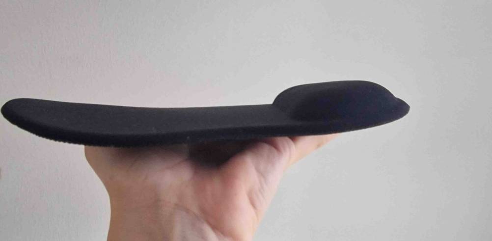 Im Test: Eine Hand hält ein Handgelenkauflage für Mäuse seitlich vor eine helle Wand.