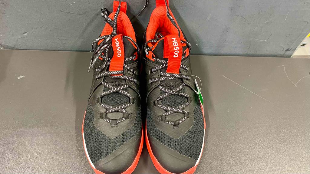Auf dem Boden befindet sich ein Paar getestete Handballschuhe für Herren in der Farbe Schwarz-Rot.