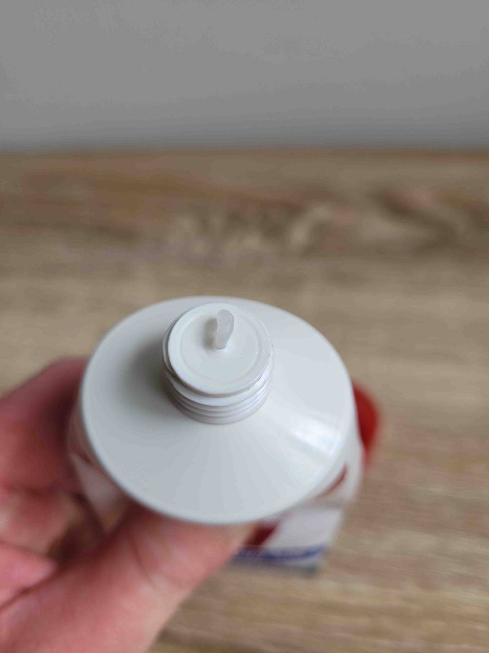 Eine Handcreme für sehr trockene, rissige Hände im Test: Eine Hand drückt Handcreme aus einer Verpackung heraus. 
