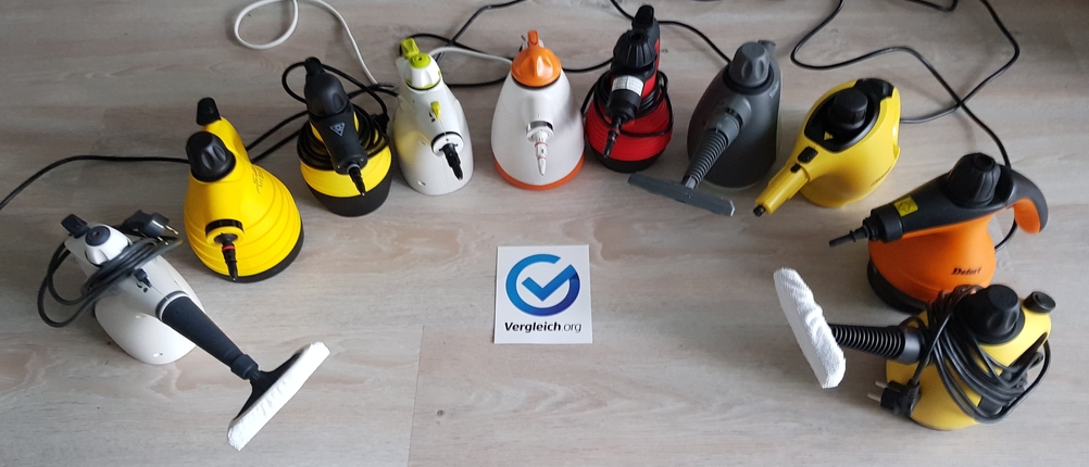 Handdampfreiniger im Test: viele verschiedene Geräte stehen auf einem Boden