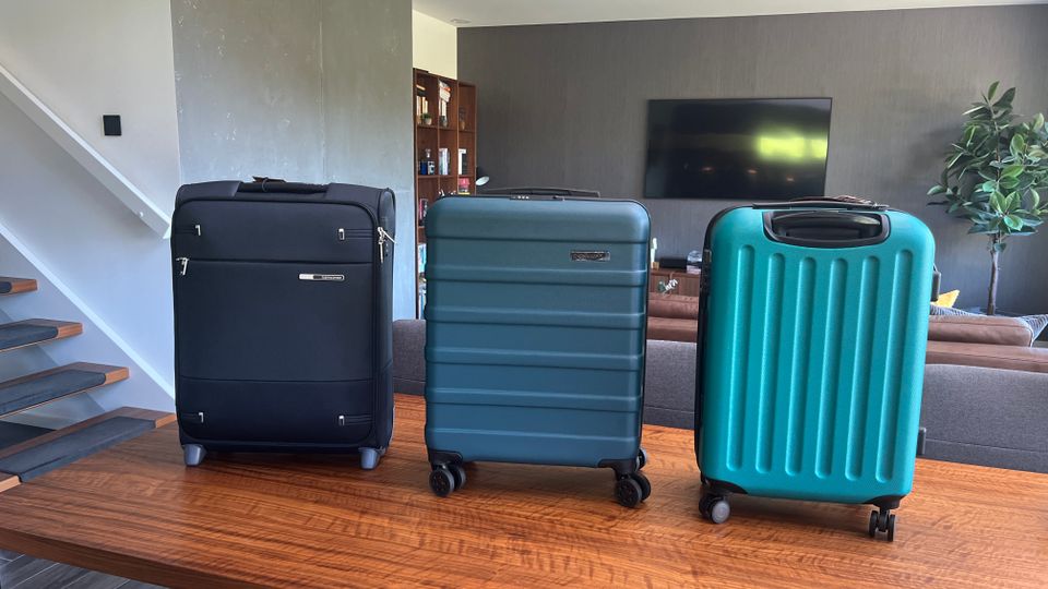 Drei Handgepäck-Koffer stehen nebeneinander auf einem Holztisch.
