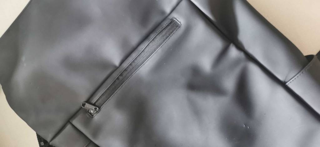 Vorderseite von einem schwarzen handgepaeck-rucksack mit Zipper.